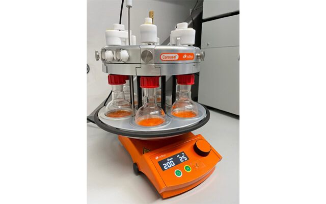 Carousel 6 being used for sustainable research to extract astaxanthin from crustascean waste. The liquid in the flasks is bright orange.